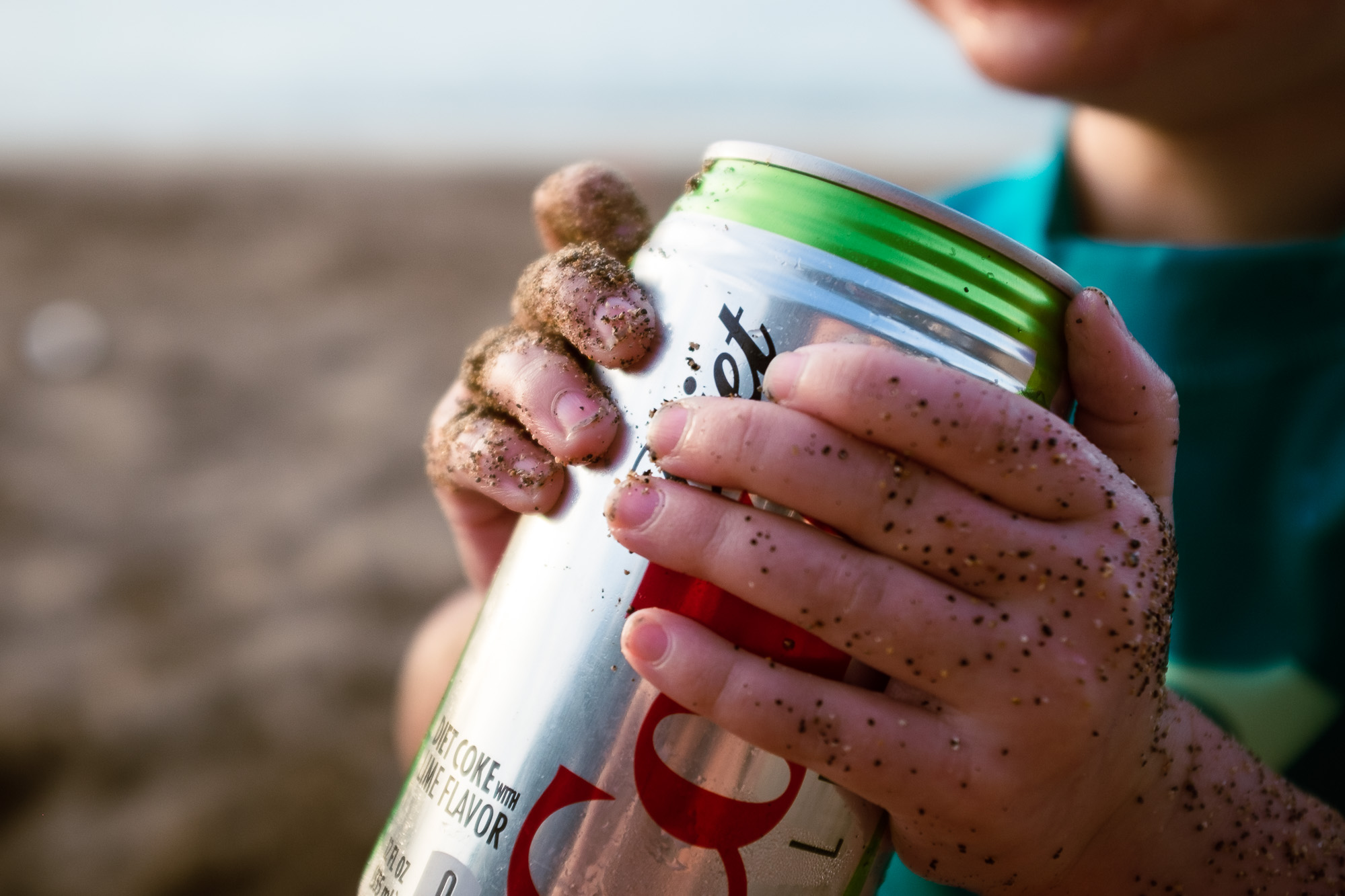 A little girl holds a can of Diet Coke while spending time at the beach