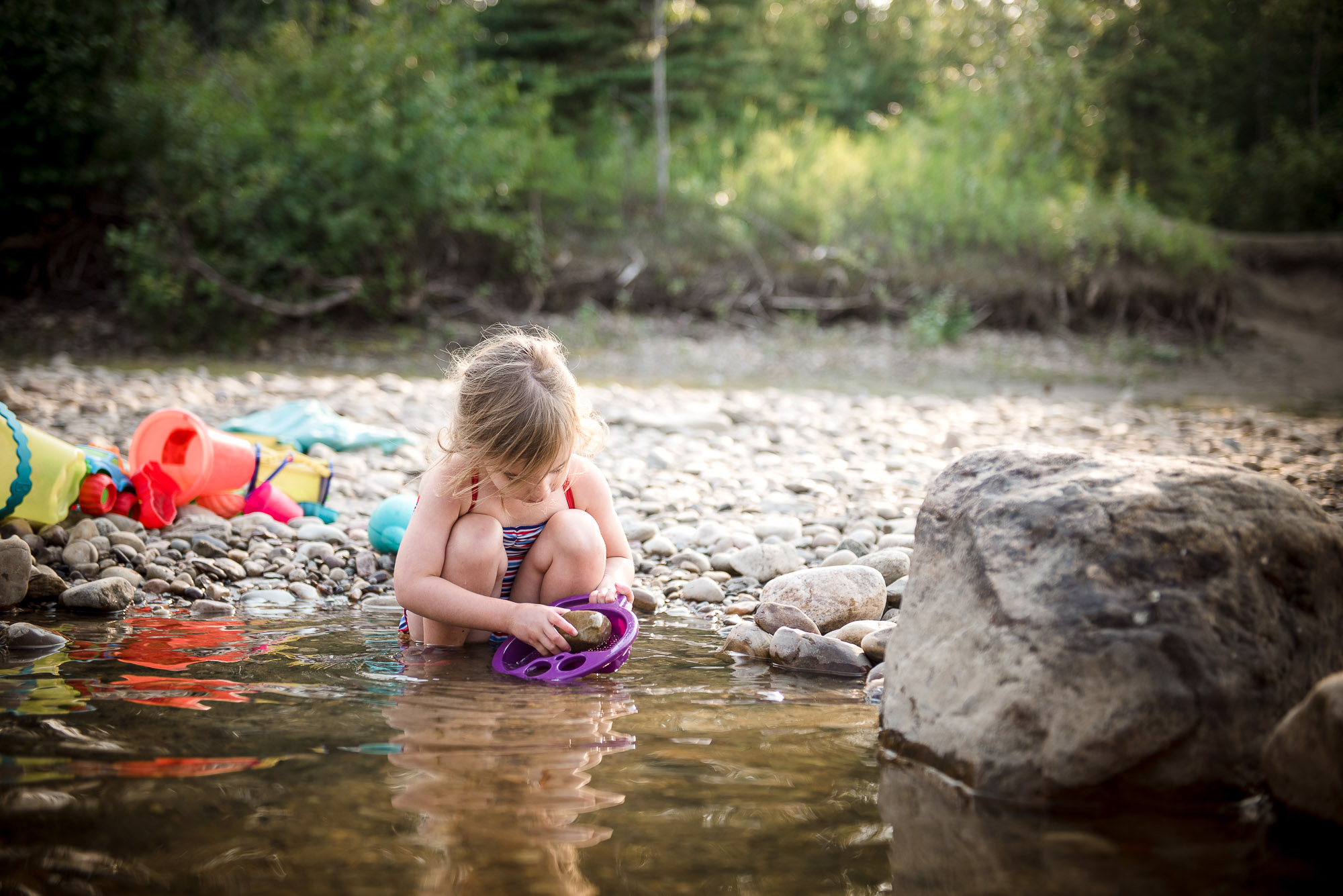 a little girl plays in the water at Pembina River in Alberta