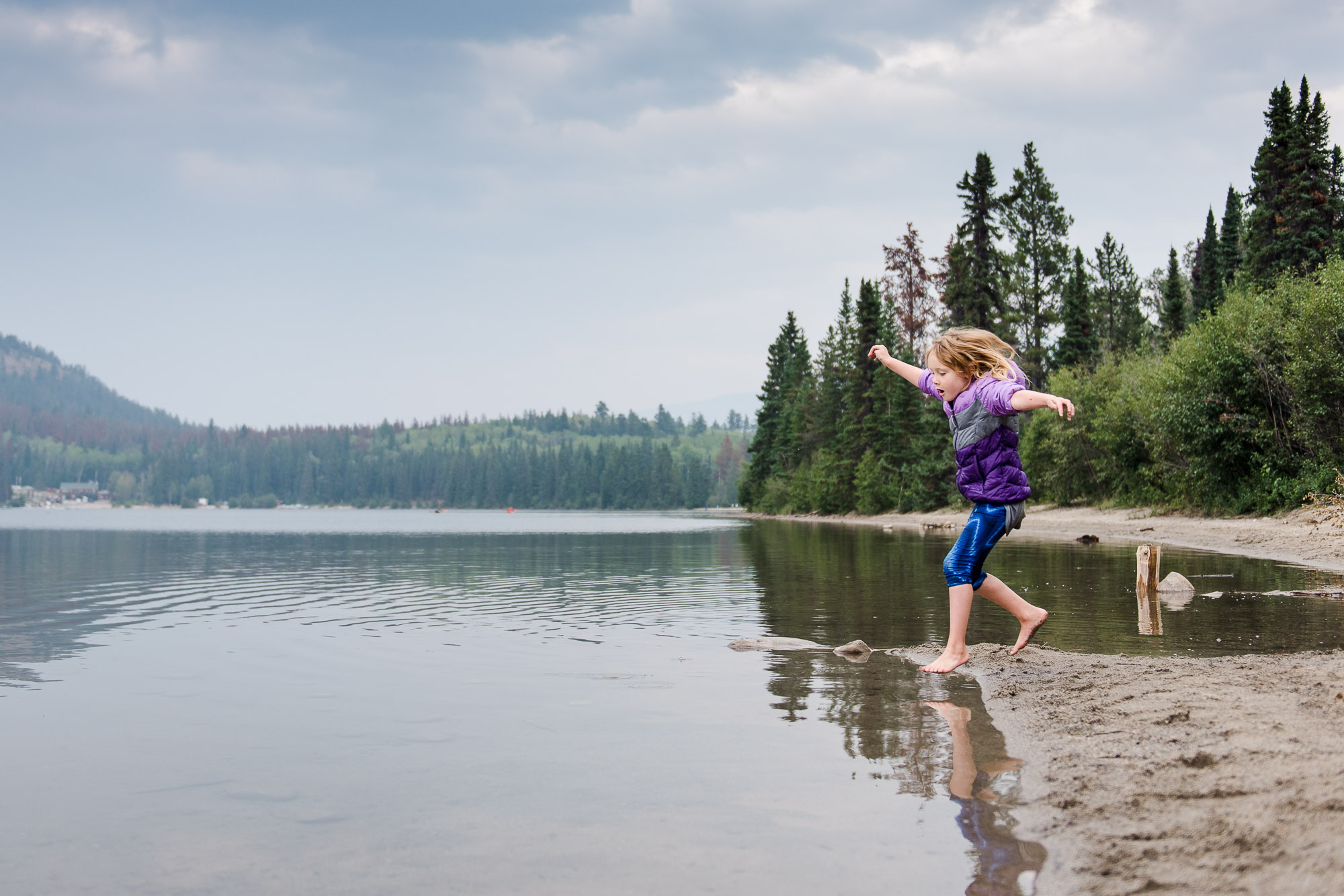 A girl jumps into a lake in Jasper National Park