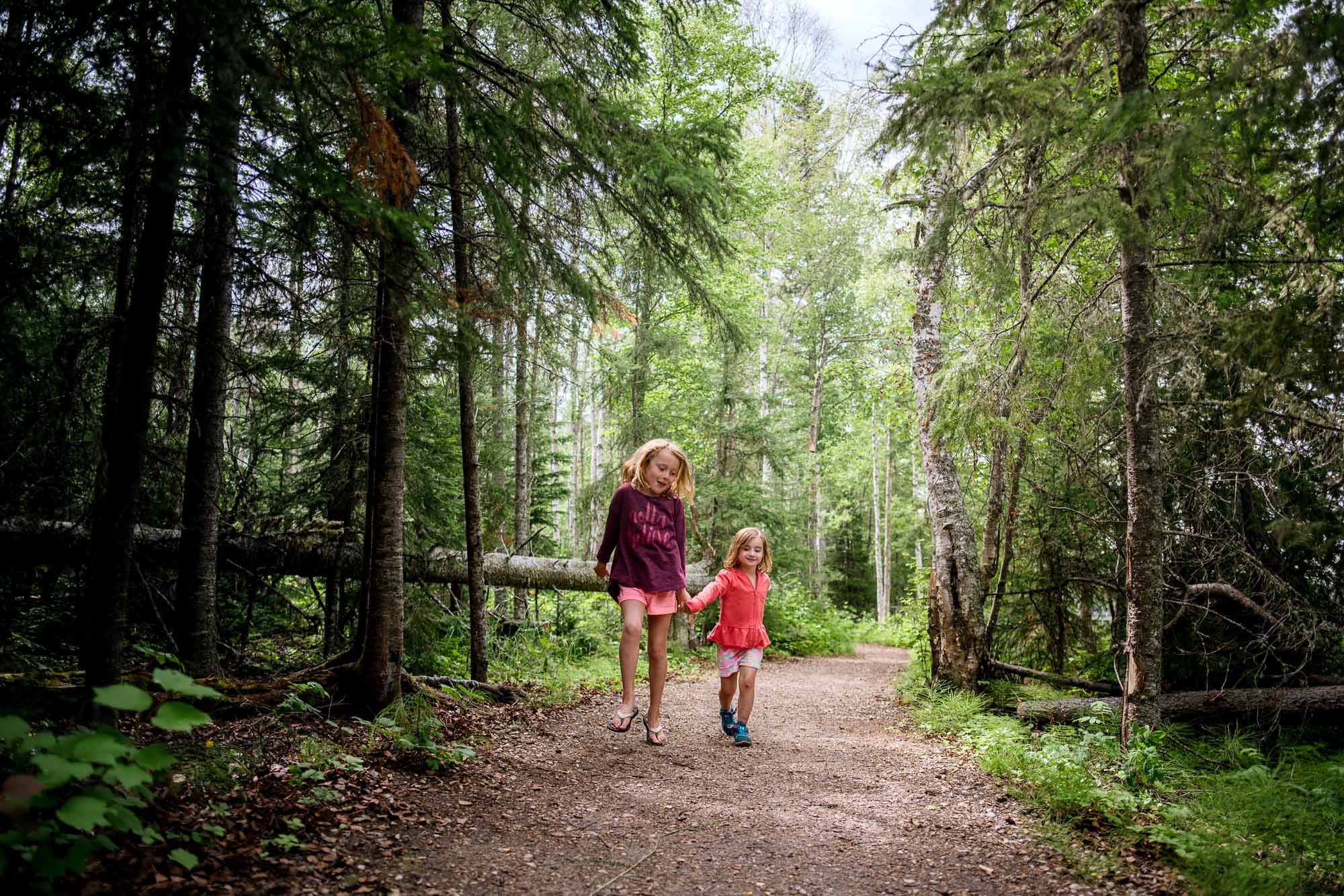 2 sisters skip through the forest at Carson Pegasus Provincial Campground near Edmonton and Whitecourt. 