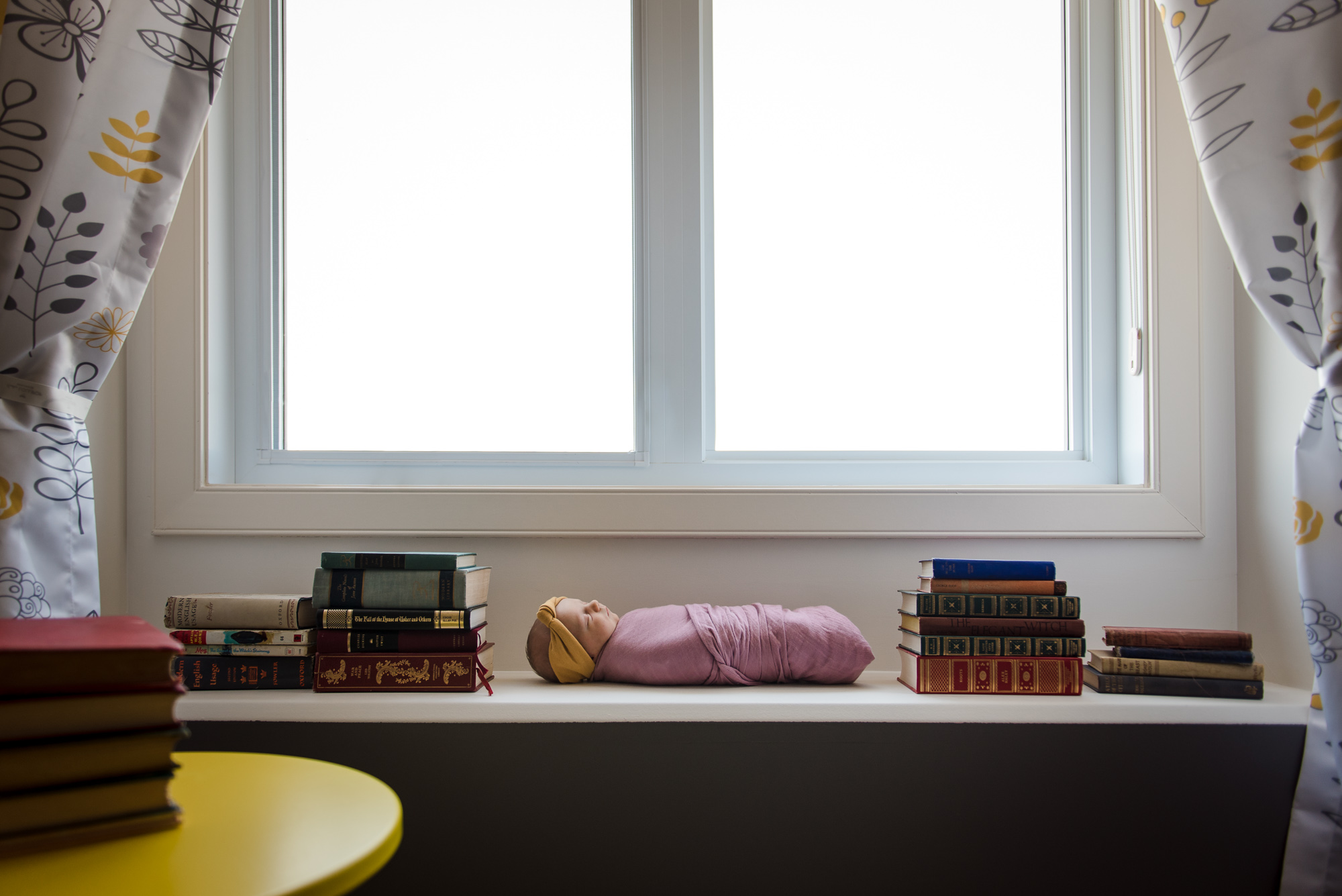 A newborn baby surrounded by books during a Sherwood Park newborn session