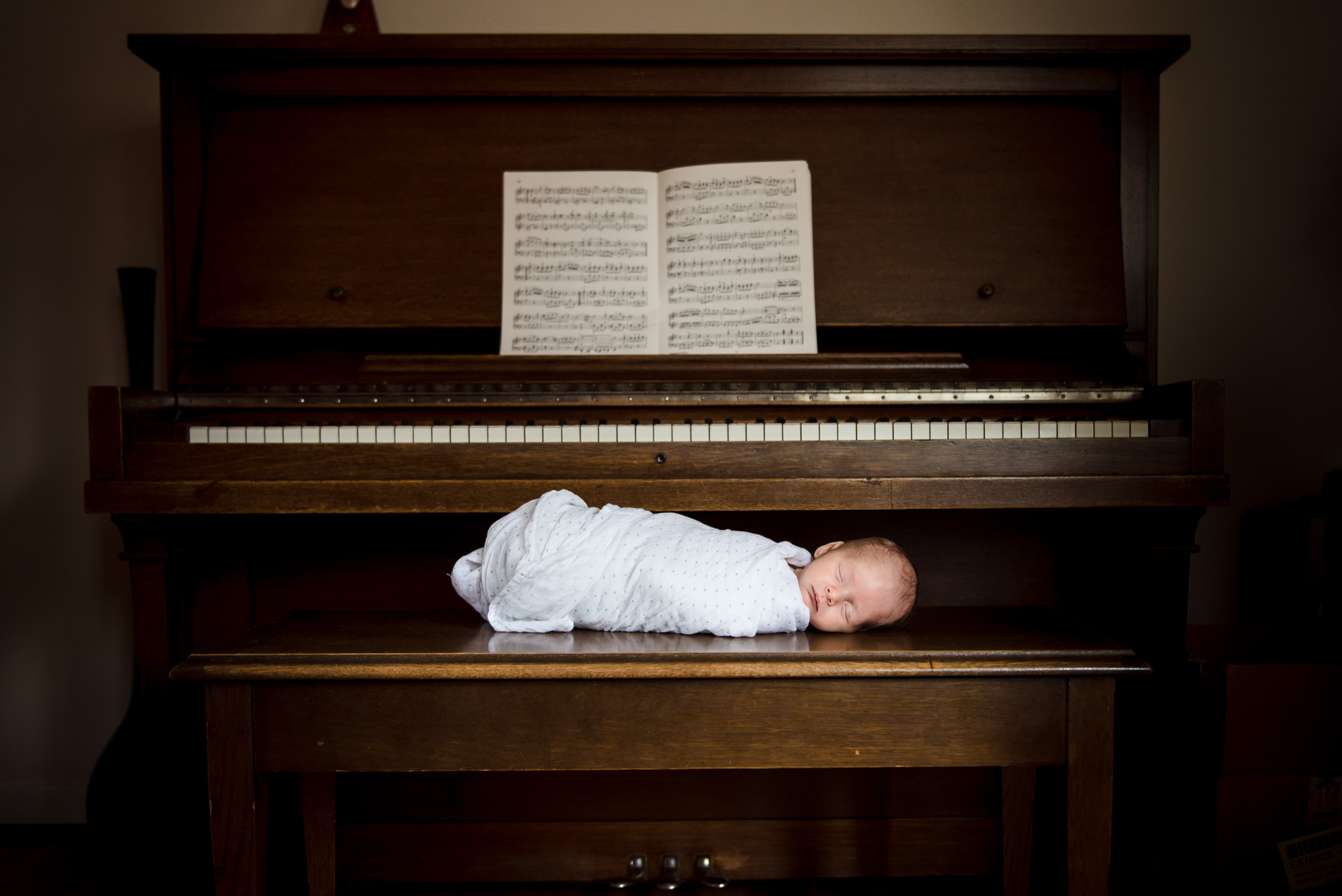 A baby swaddled on a piano in an Edmonton home
