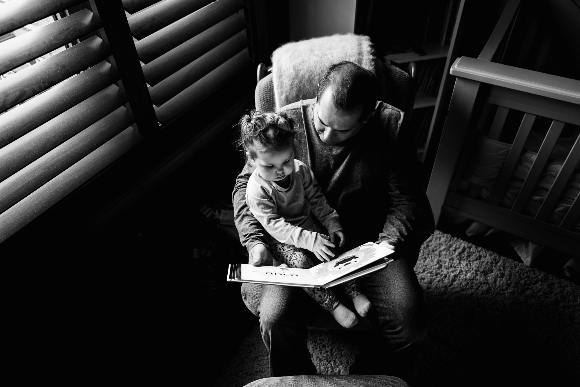 A dad reads a book to his daughter 