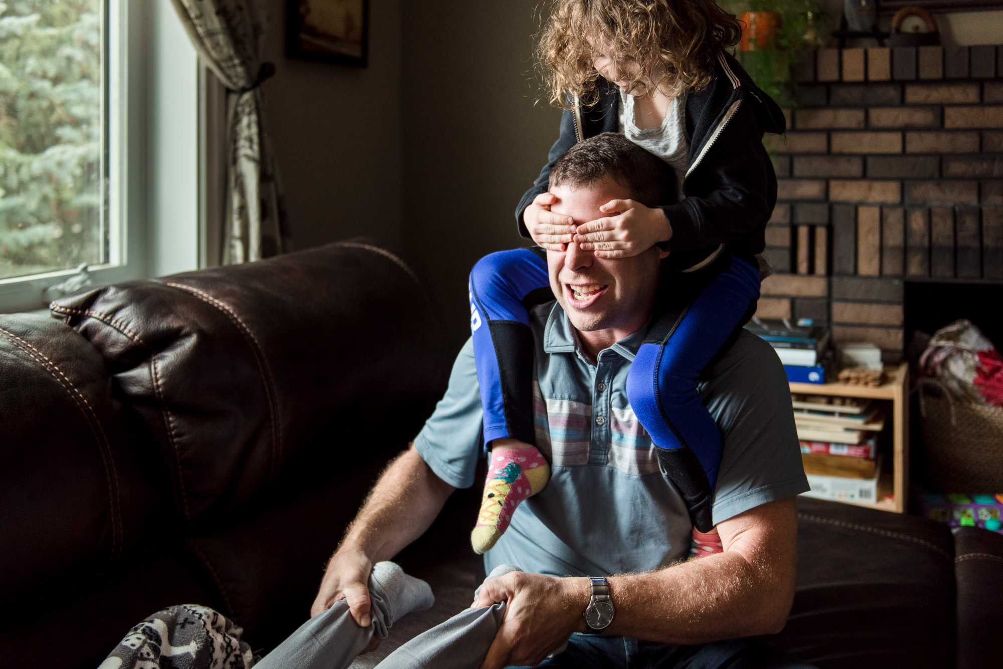 A girl wrestles with her Dad in their Edmonton home. 