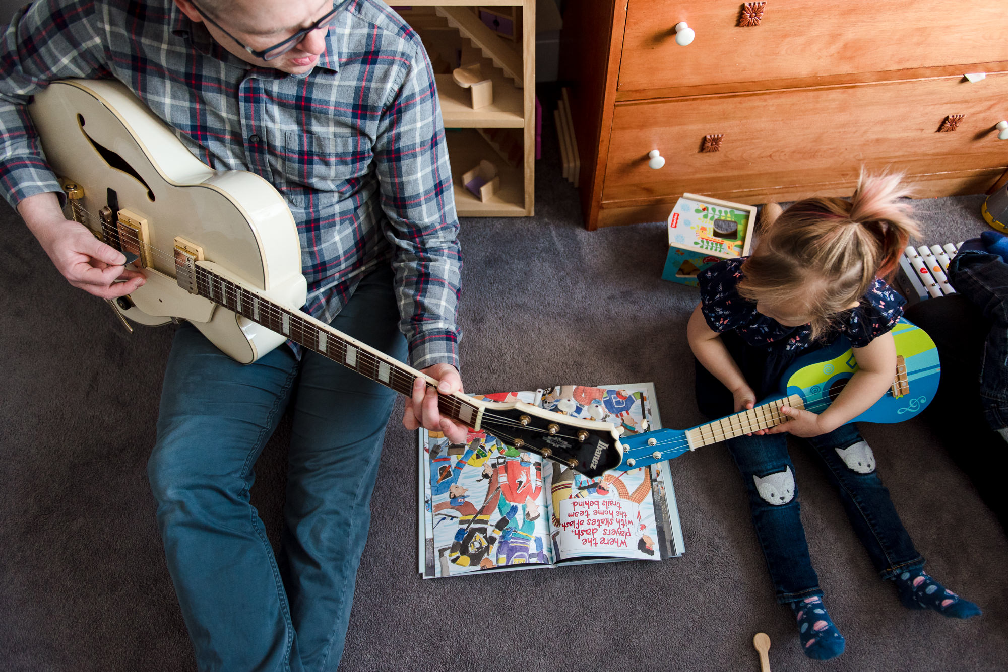A Dad plays music with his young daughter as part of a family photo session in their Edmonton home. 