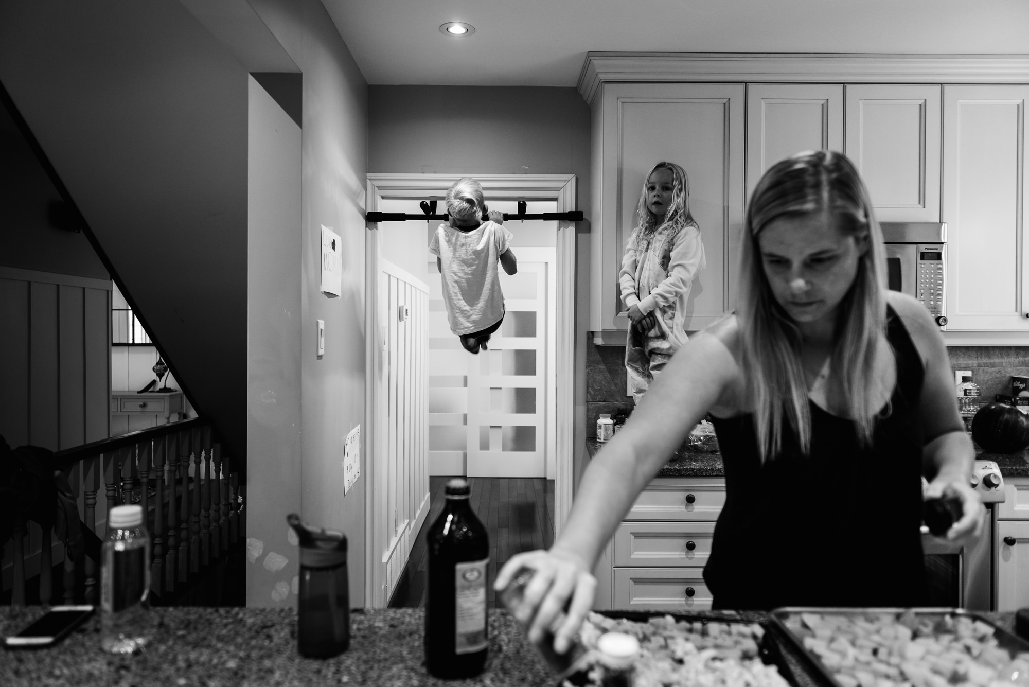 A little boy does chin ups while his mom cooks dinner in their central Edmonton home