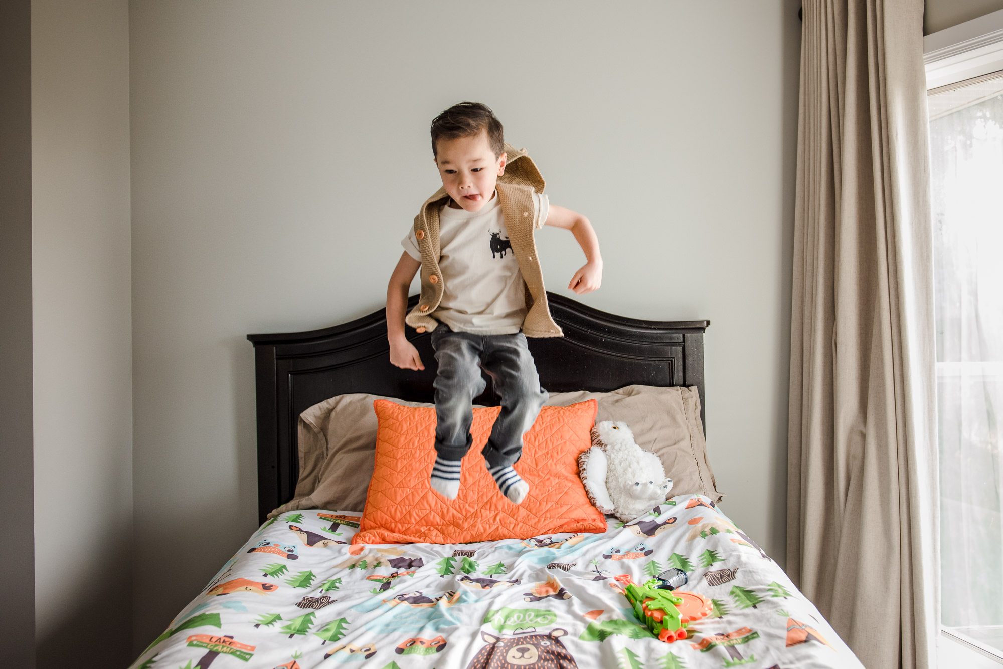 A boy jumps on a bed during edmonton family photography
