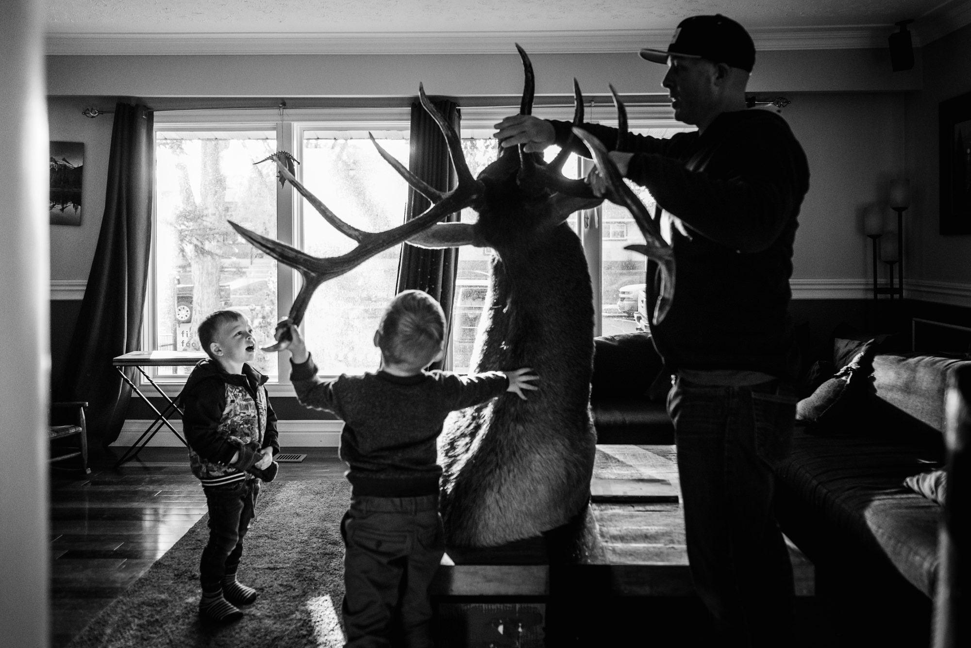 A dad and his sons measure an Elk head as part of their annual family photo session