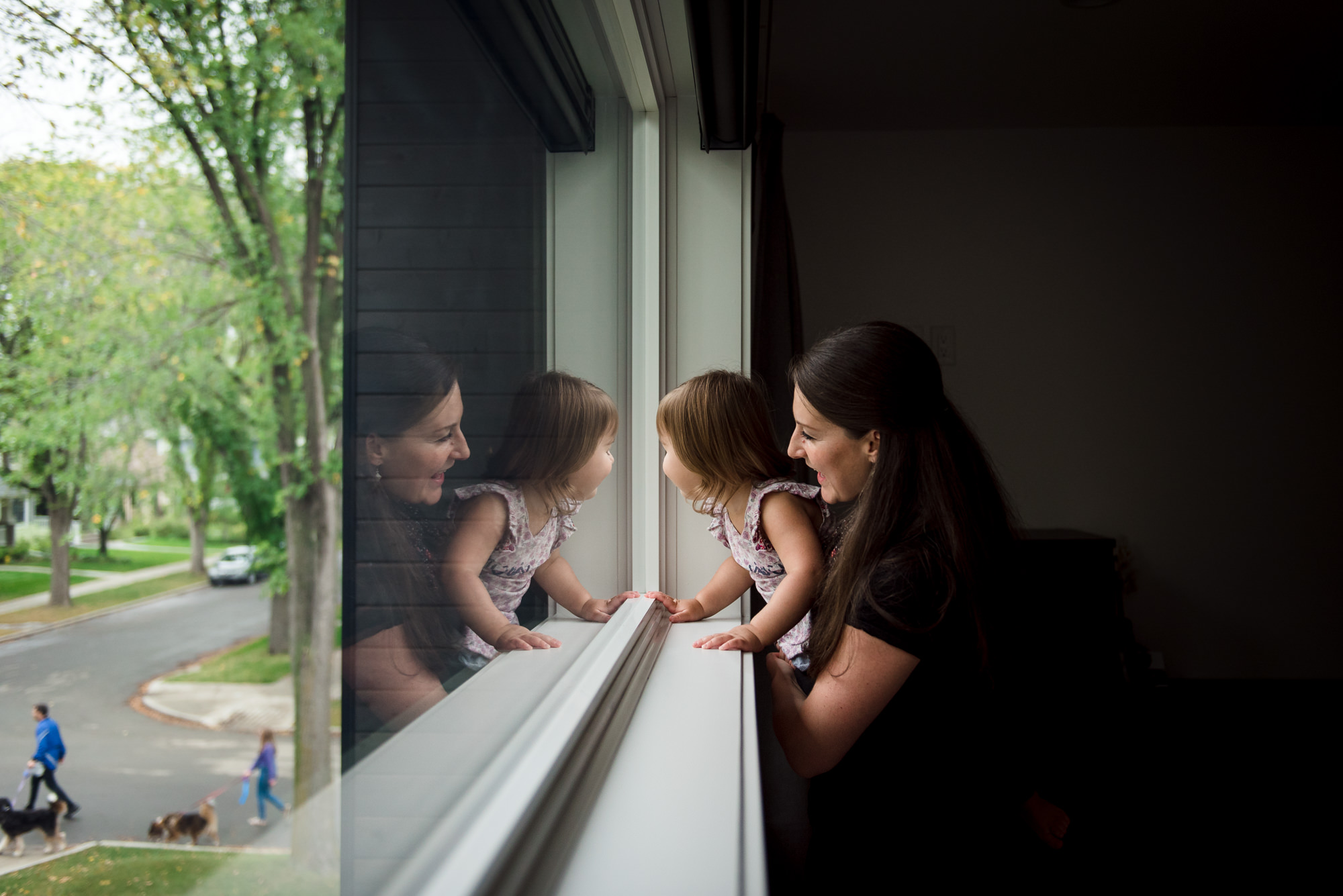 A mom looks out the window with her daughter in their Edmonton home. 