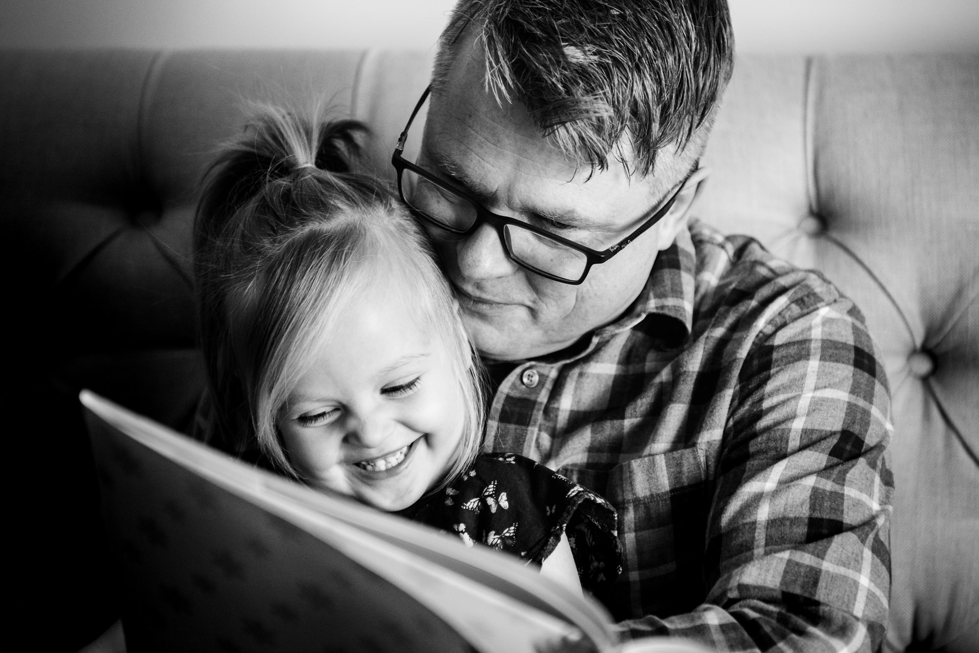 A dad snuggles a little girl during a lifestyle family photo session in Edmonton