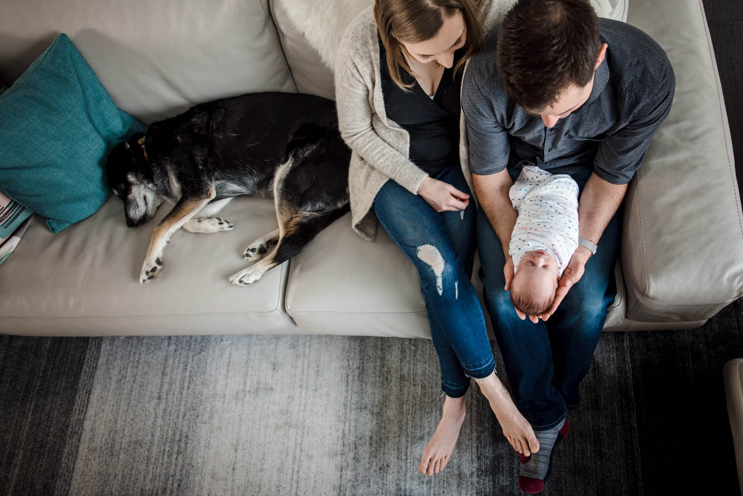 A family sits in their edmonton home with their dog and newborn baby. 
