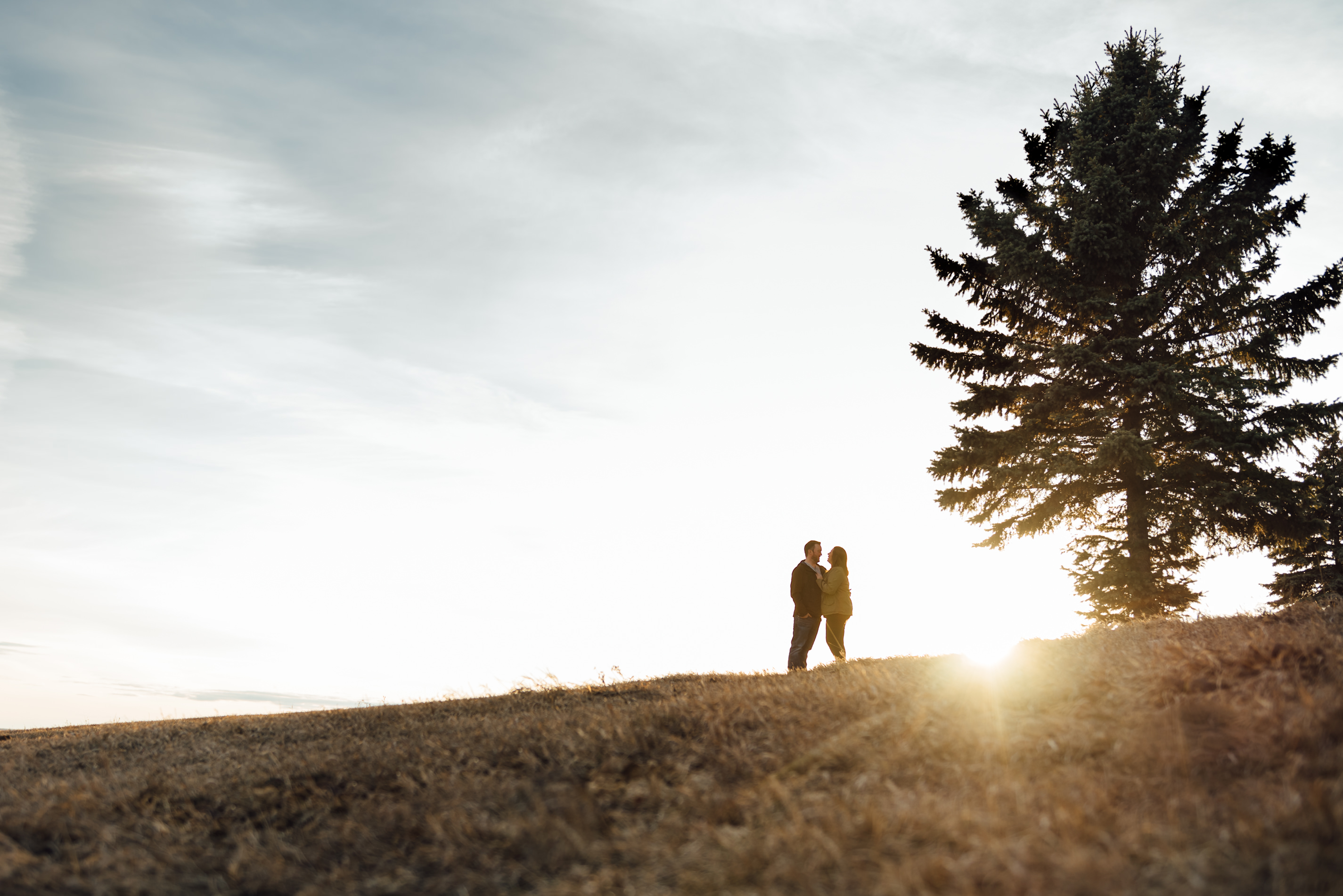 A couple hugs in a field outside of Edmonton, Alberta during a couples photo session by Fiddle Leaf Photography 