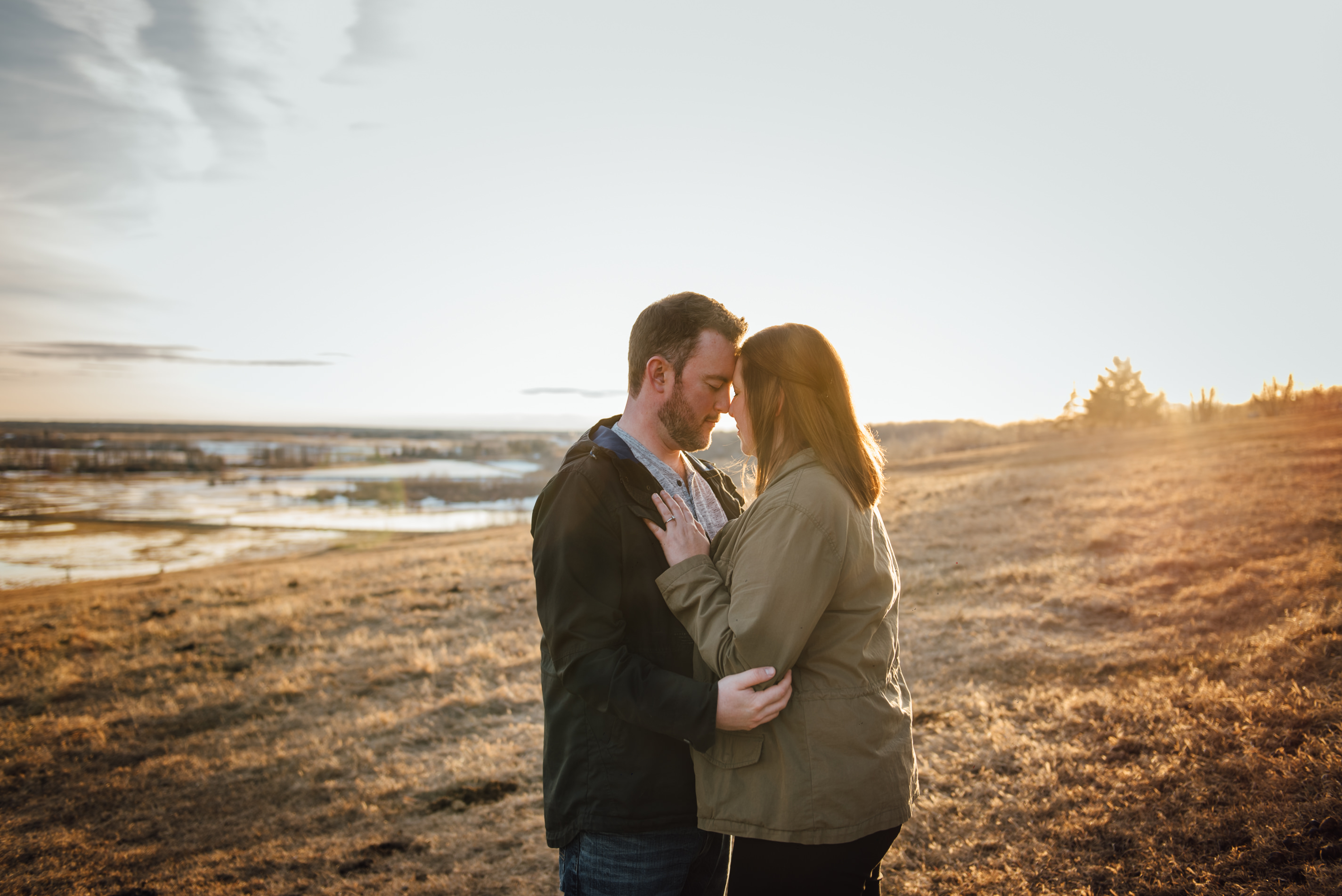 A couple stand in a golden field outside of Edmonton as part of a couples photo session