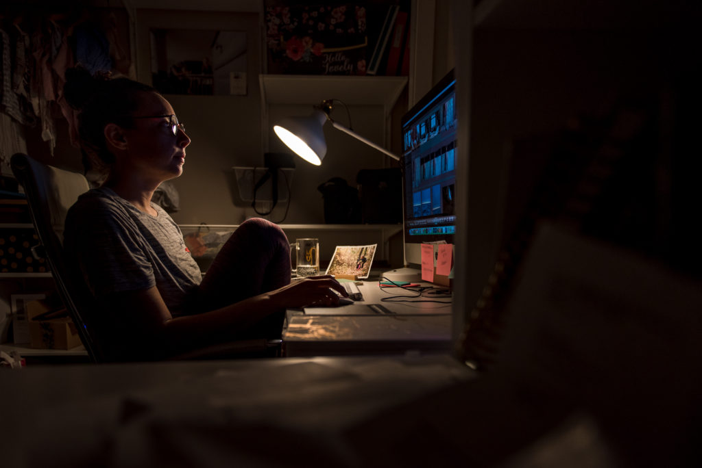 An Edmonton photographer sits at her desk editing newborn and family photos