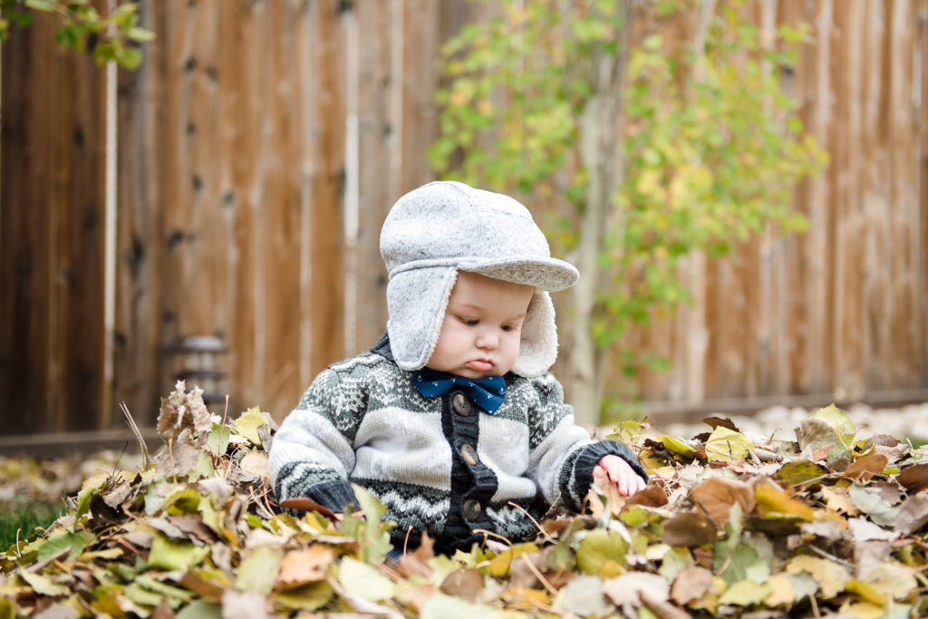 A little boy sits in a leaf pile by Edmonton Photographer Family Fiddle Leaf Photography