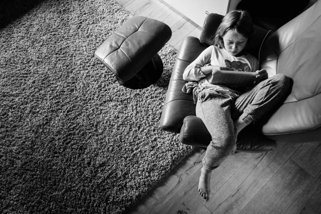 A girl watches a tablet in this black and white image