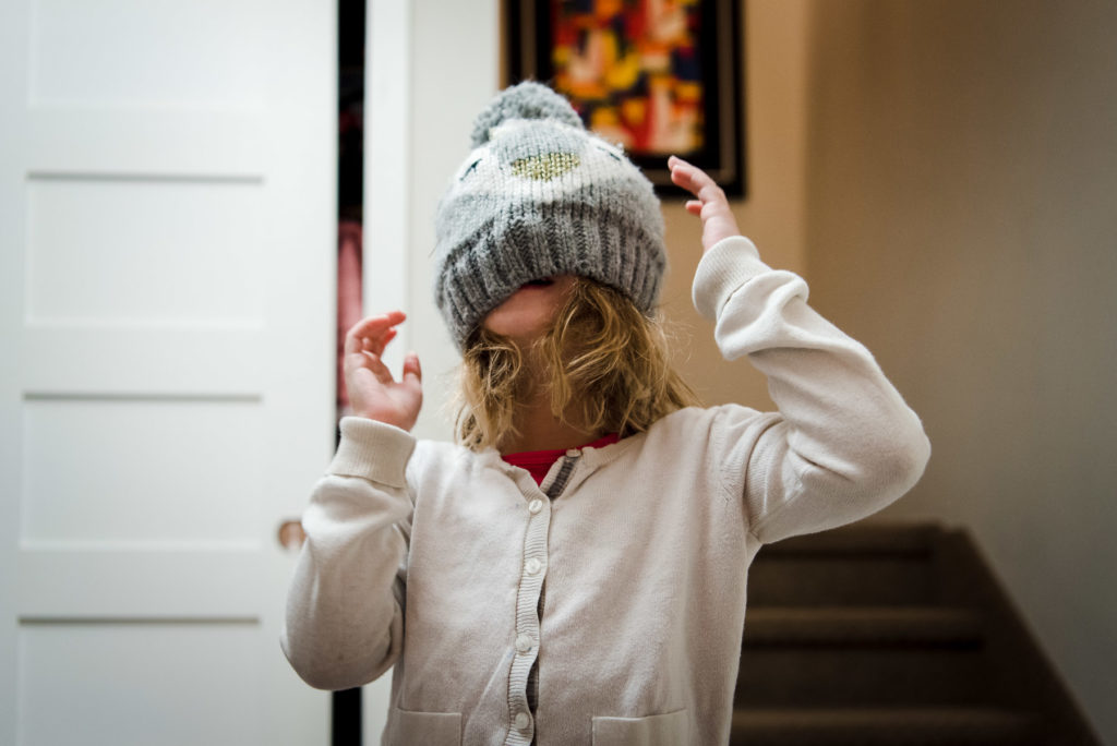 A girl pulls on a winter hat in her Edmonton home