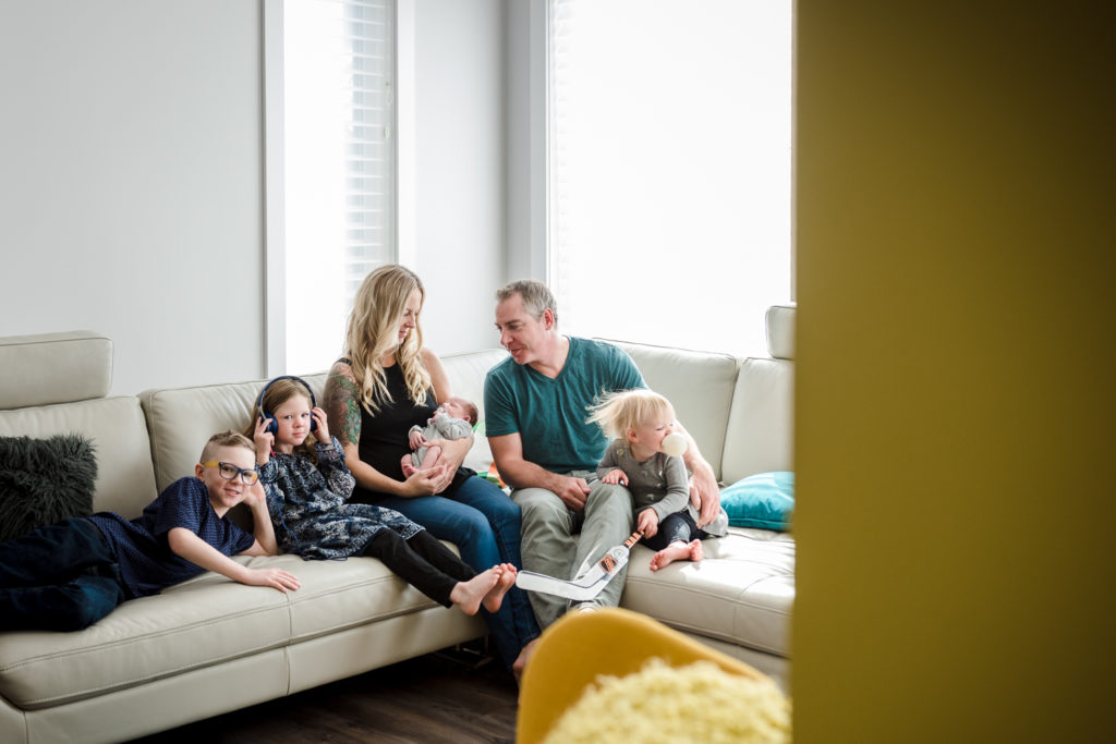 A family sits in their St. Albert living room during an in-home newborn photo session with older siblings