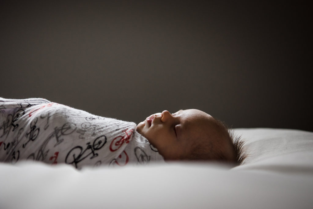 A newborn baby sleeps during his newborn pictures