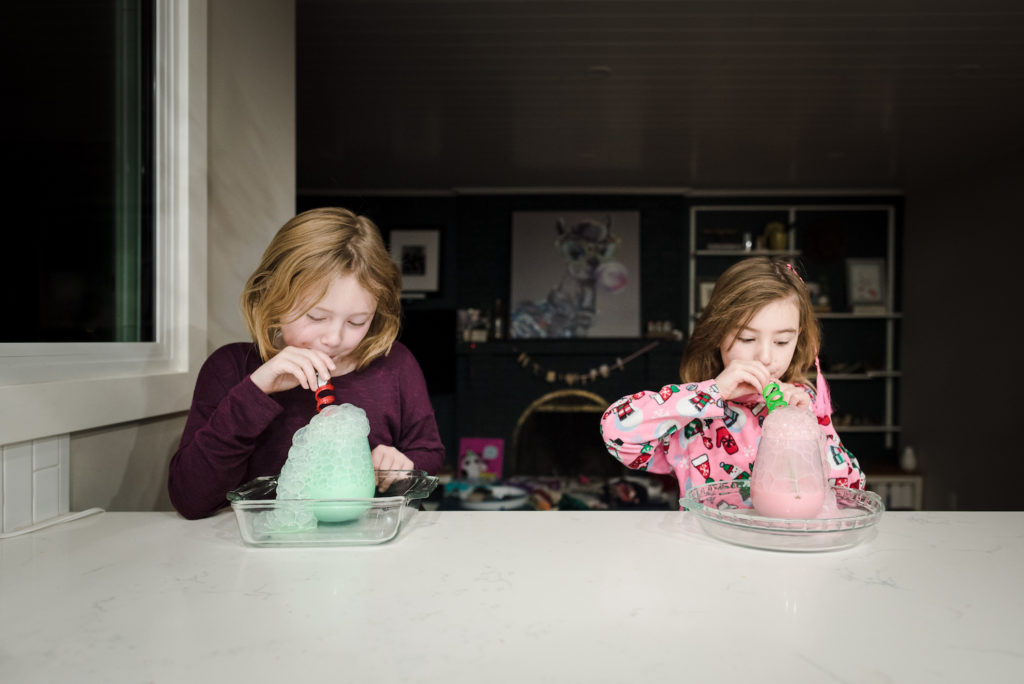 Girls blow bubbles in milk during a quick and easy Christmas activity