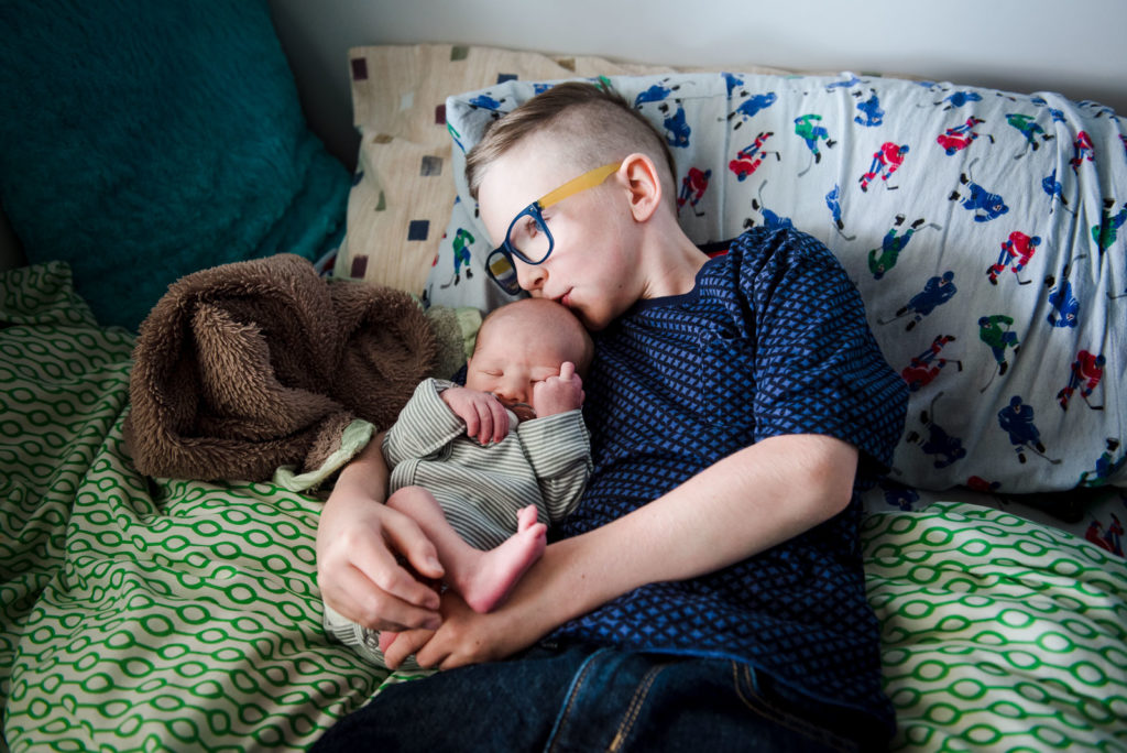 A big brother cuddles his new baby brother during an in-home newborn photo session in St. Albert