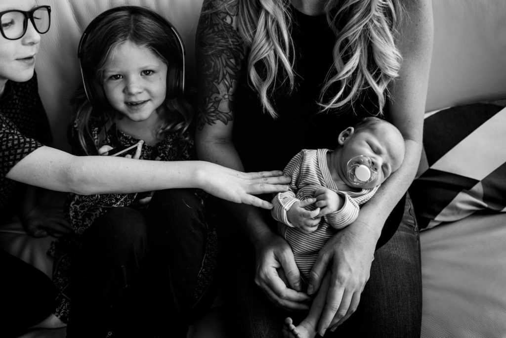 A mom holds a baby while siblings are nearby during a photo session in their St. Albert home. 
