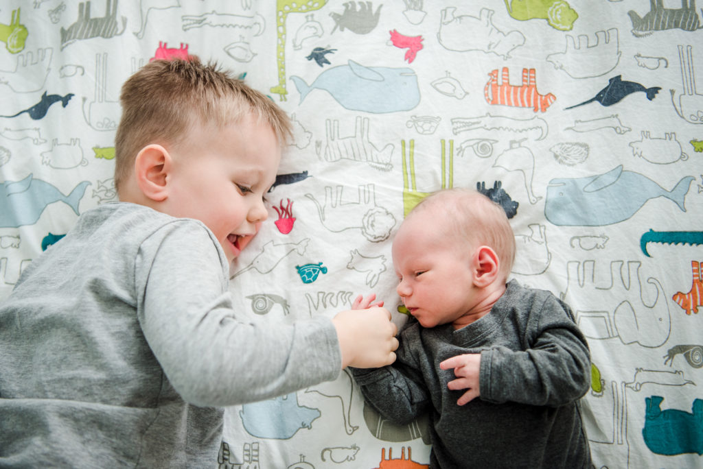 A young boy talks to his newborn baby brother during a casual newborn photo session in his Edmonton home. 
