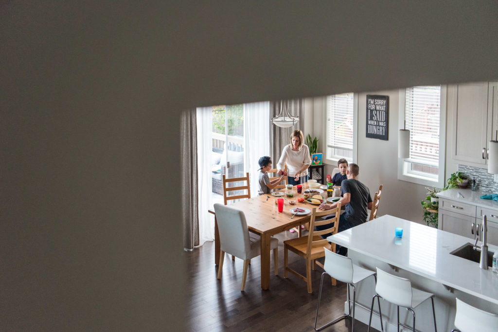 A family sits down to eat dinner during a documentary day in the life photo session in their Edmonton home