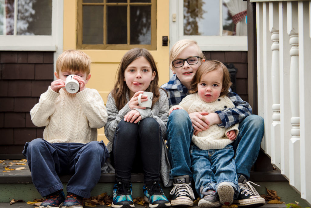 4 siblings sit on their Edmonton porch drinking hot cocoa during a family photo session 