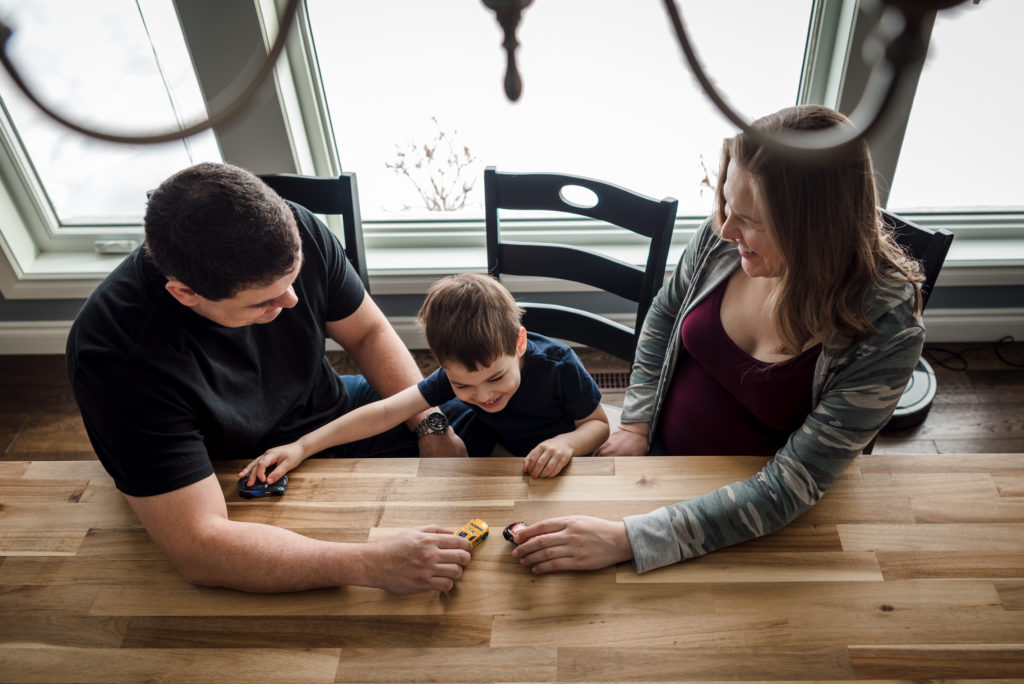 Parents play Hot Wheels with their son during an Edmonton Maternity Photo Session by Kelly  Marleau of Fiddle Leaf Photography 