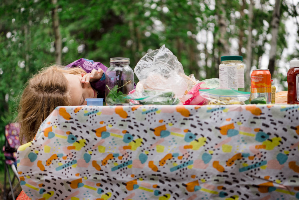 a girl looks into a bug jar while camping in Alberta. Items to bring camping with kids
