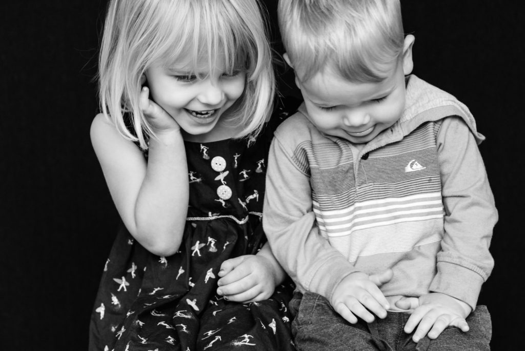 a brother and sister giggle during school photos in Edmonton