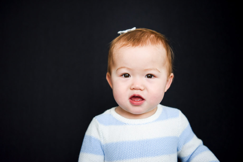 A 6 month old little girl looks at the camera during a portrait. 
