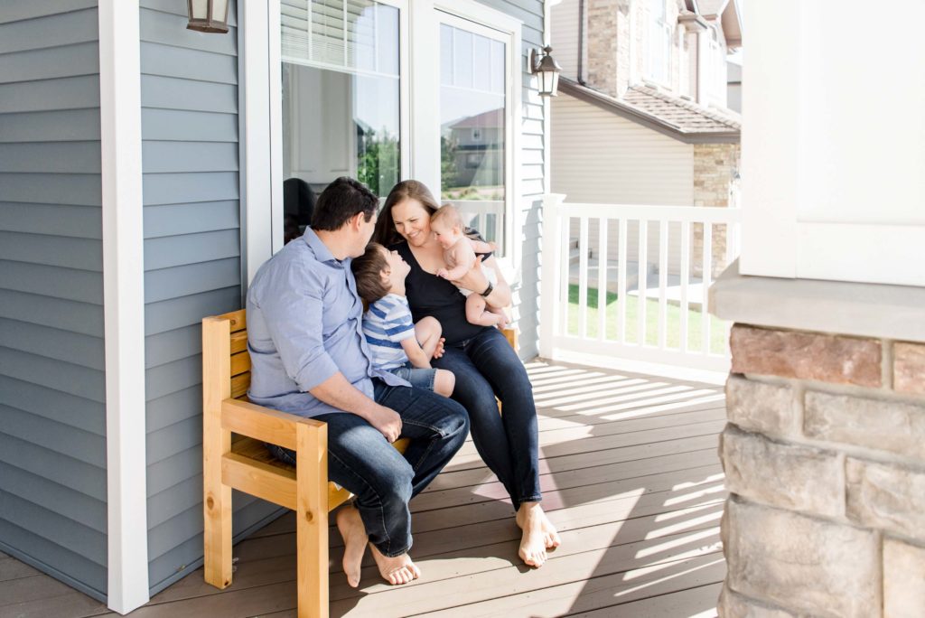 A family sits on their porch during a family photo session in their Edmonton home. 