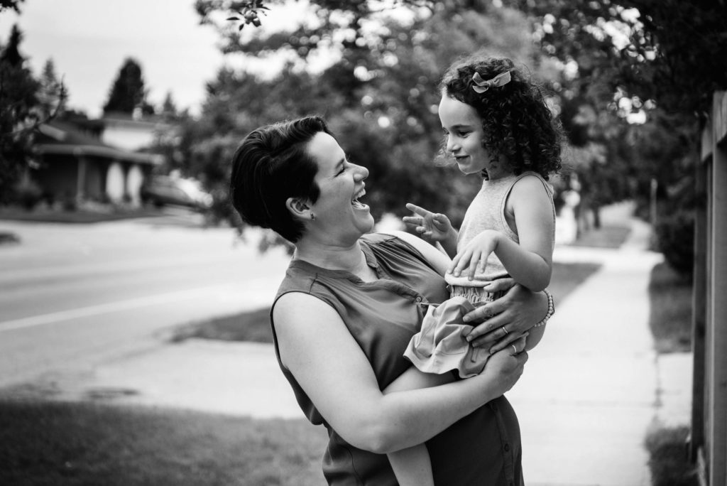 A mom and daughter giggle together while picking cherries from a tree in their Edmonton neighbourhood. 