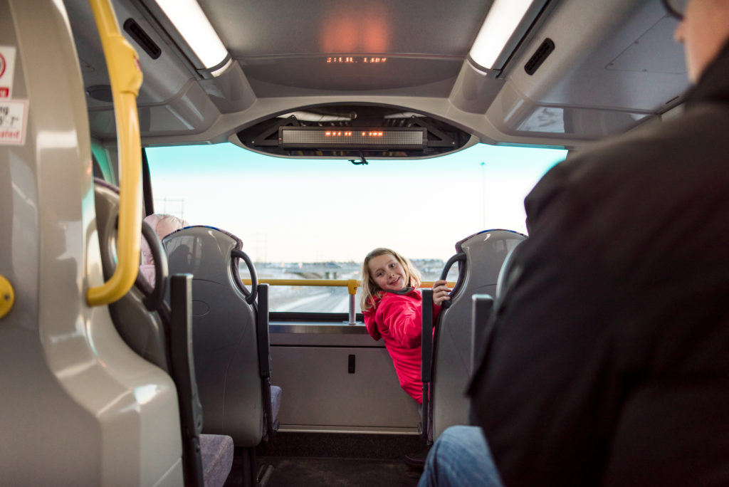 A girl smiles while riding a double decker bus in Strathcona County
