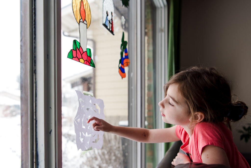 A little girl looks at a paper 
snowflake she made