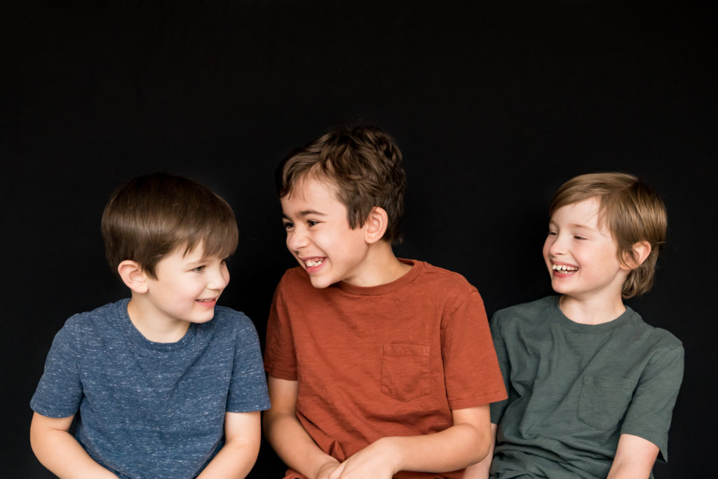 School photos what to wear. 3 brothers photographed in blue, orange and green shirts, laughing